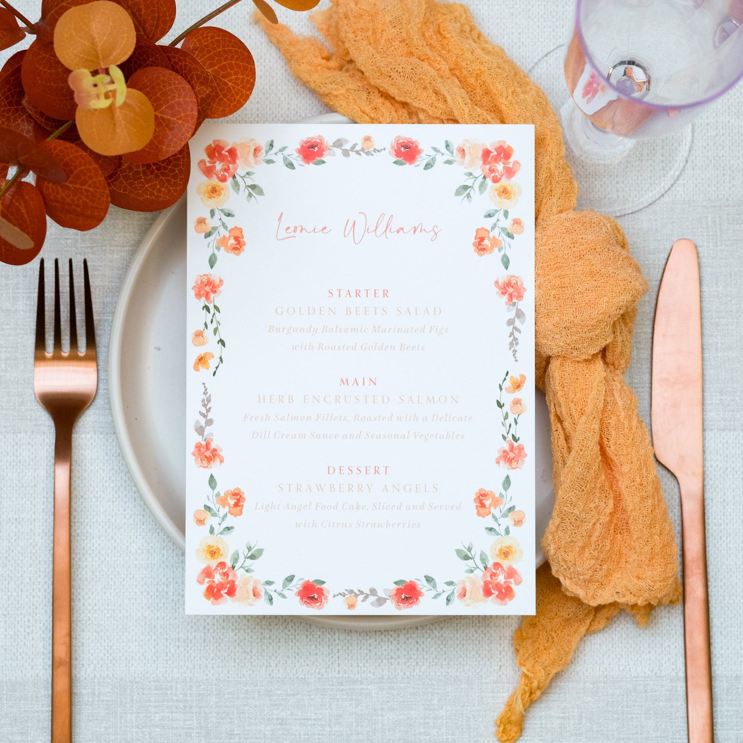 Orange wedding place setting with menu with orange floral border, copper cutlery and orange napkin