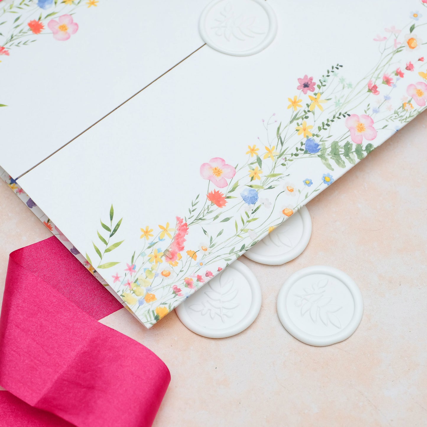Folded wedding invitation with wax seal and illustrated wildflowers