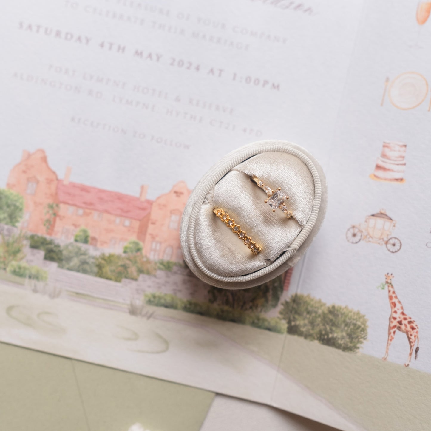 Rings with safari folded wedding invitation in background
