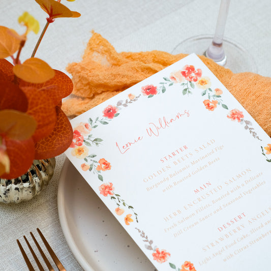 Orange wedding menus customised with guest names in orange text with orange floral border
