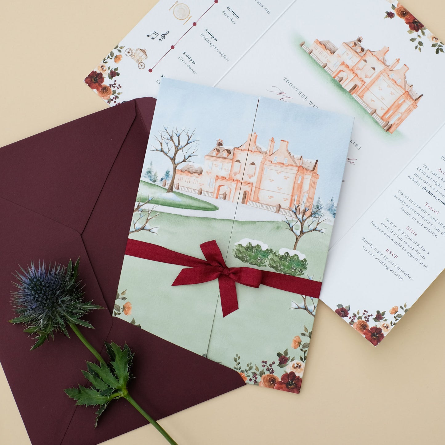 Folded wedding invitation with illustration of Sorn Castle, burgundy envelope and ribbon