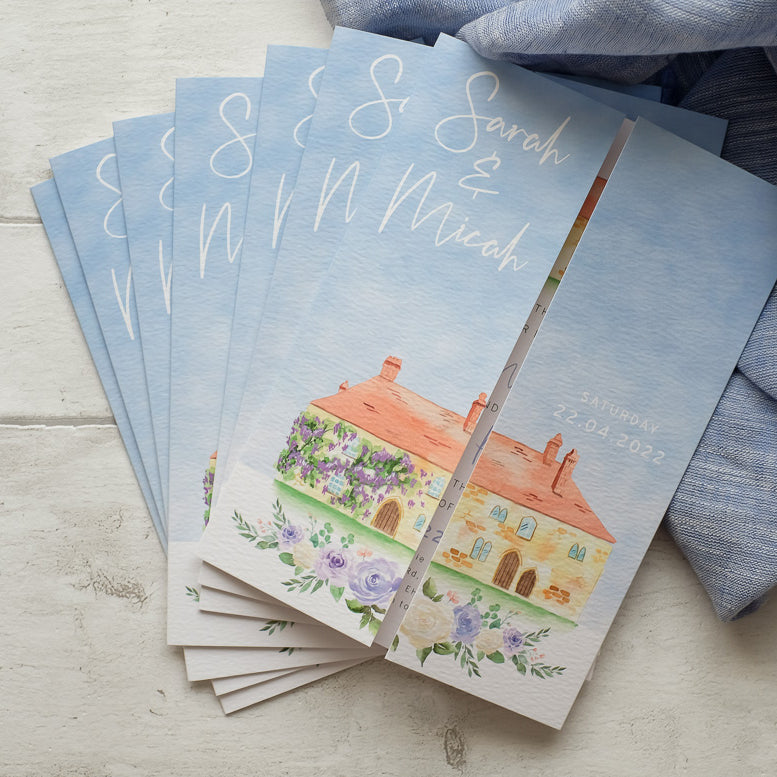 Stack of folded wedding invitations with venue illustrations